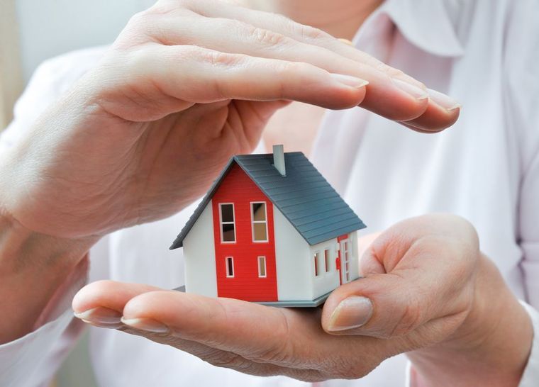 A person is holding a small model house in their hands
