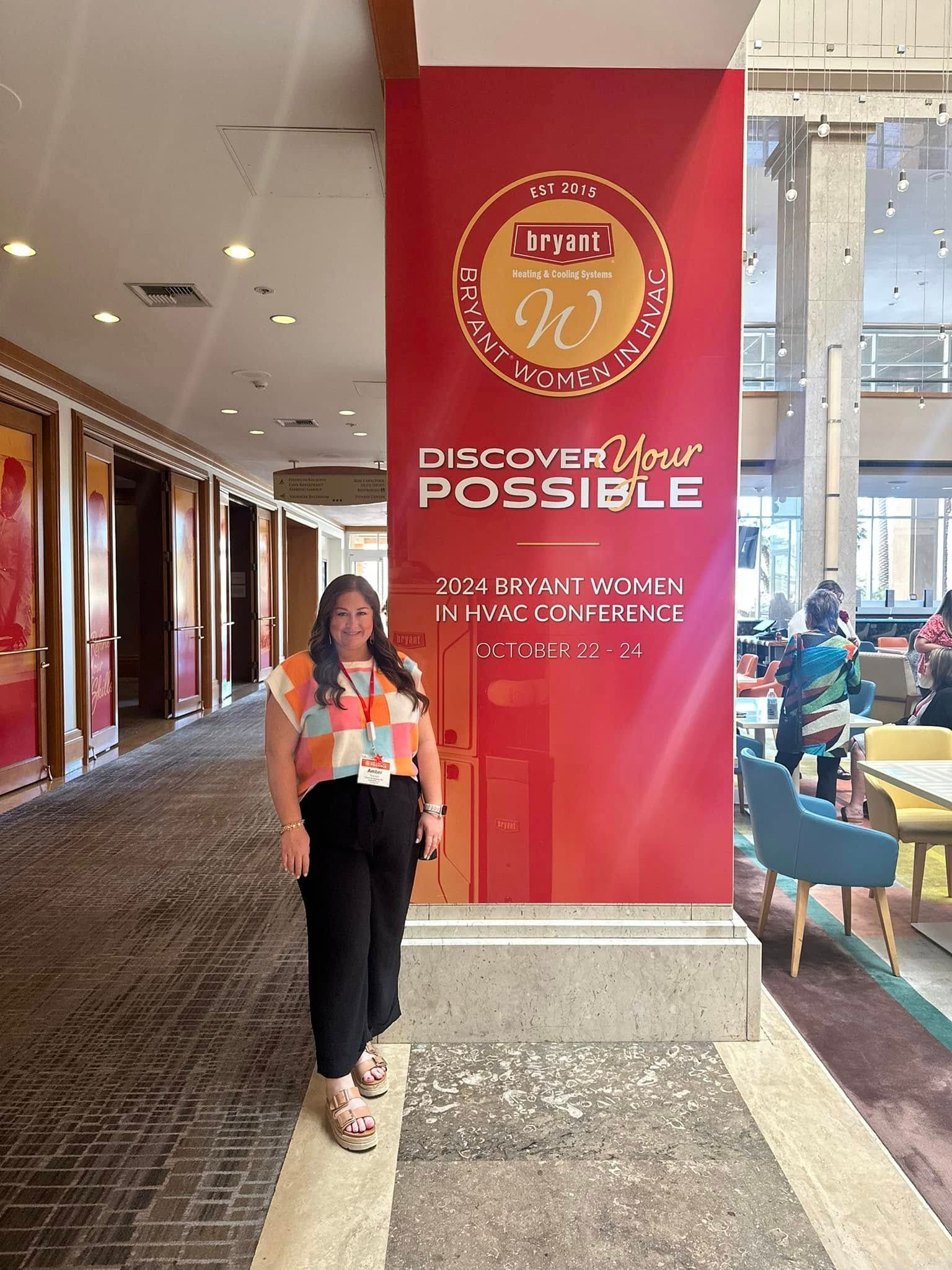 A woman is standing in front of a large red sign in a hallway.