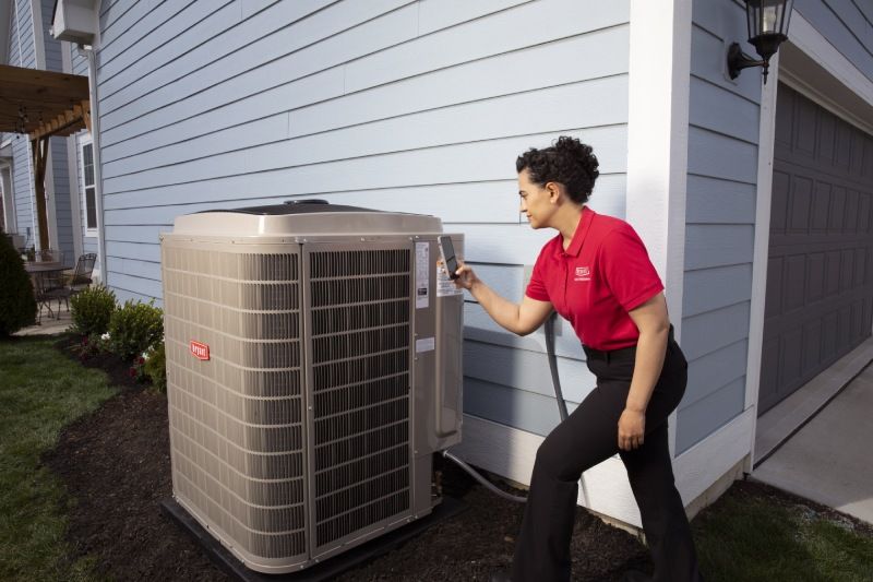 A woman in a red shirt is working on an air conditioner