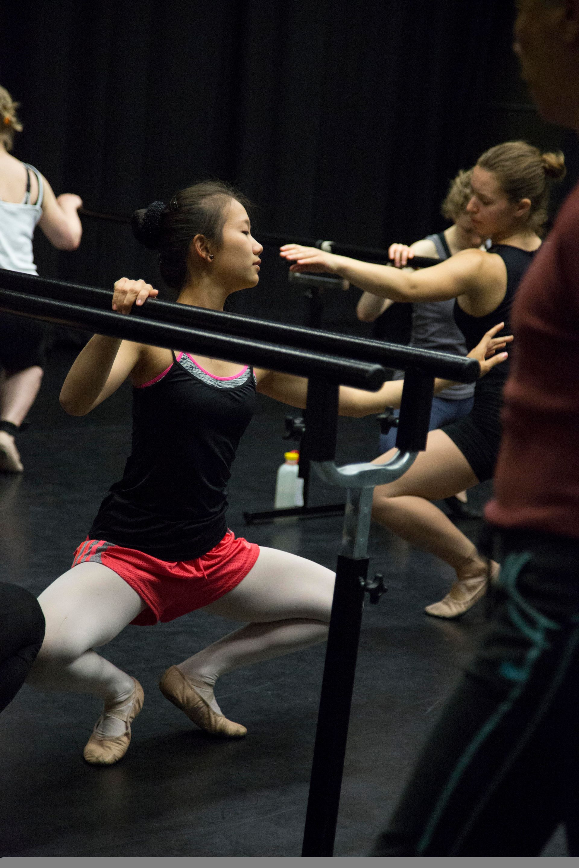Woman practicing ballet technique at the barre in ballet class