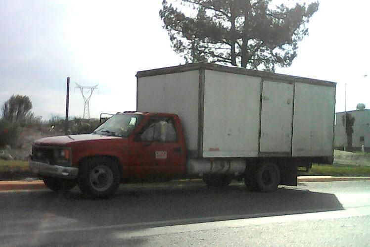 Un camión rojo con una caja blanca encima.