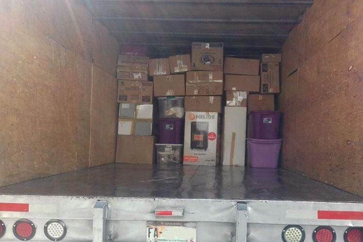 La parte trasera de un camión de mudanzas lleno de cajas y contenedores.