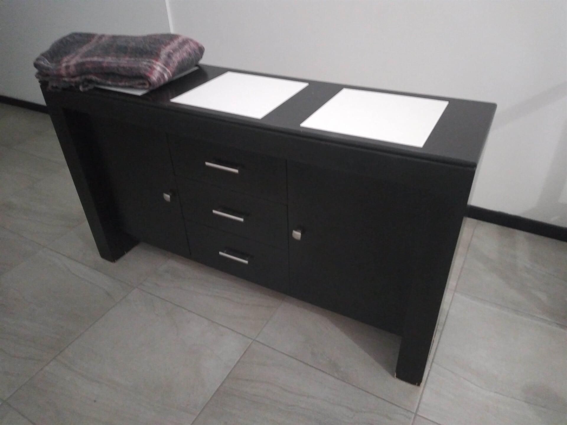 Una cómoda negra con una manta encima.