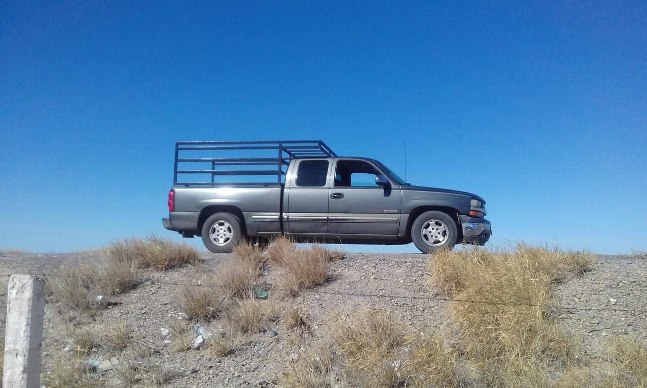 Un camión con una valla en la parte trasera está estacionado en la cima de una colina de tierra.