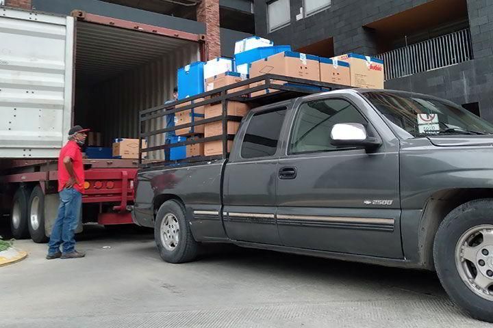 Un hombre está de pie junto a un camión con cajas en la parte trasera.