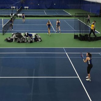 A group of people are playing tennis on indoor courts