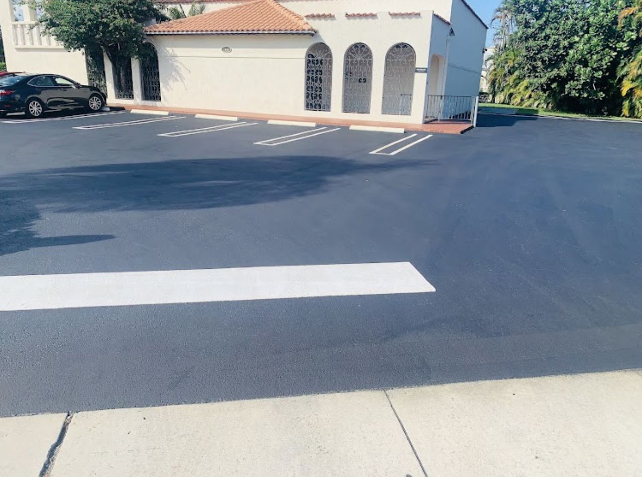 A parking lot with a white crosswalk and a white building in the background