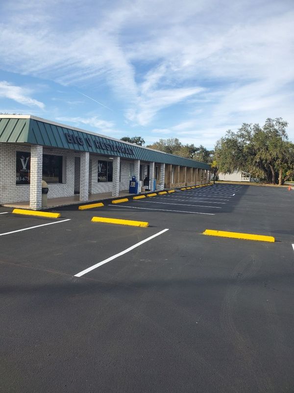 A building with a green roof and a parking lot in front of it