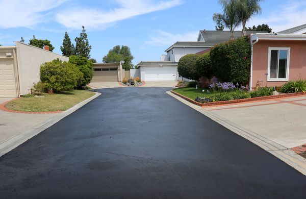 A residential neighborhood with a newly paved driveway between two houses.