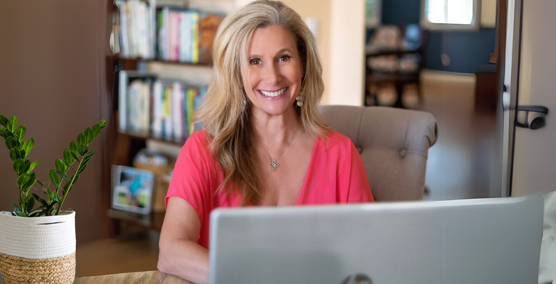 A woman is sitting at a desk in front of a laptop computer.