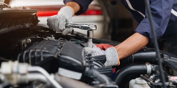 A mechanic is working on the engine of a car in a garage.