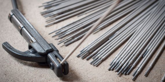 A close up of a welding machine and a bunch of welding rods on a table.