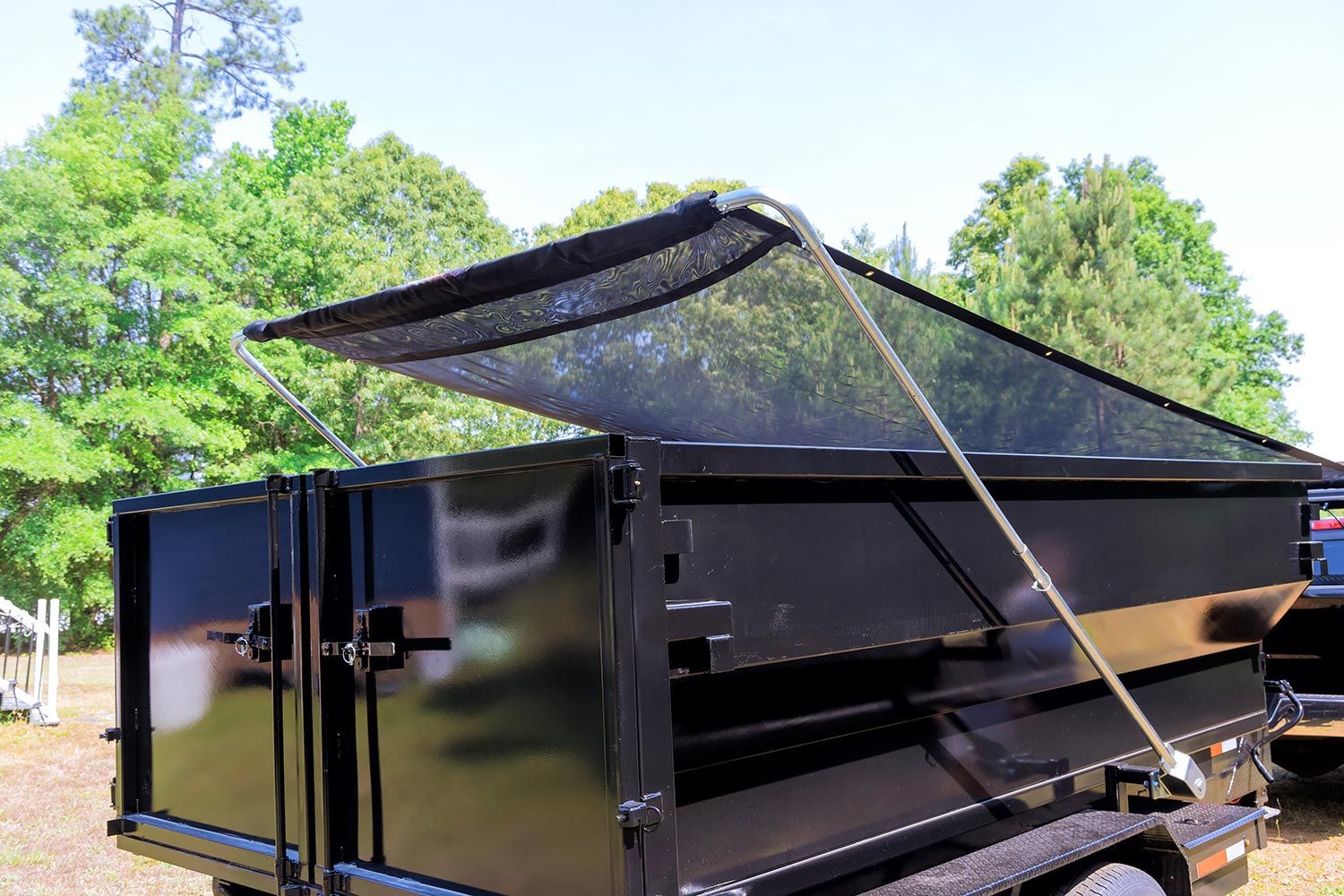 Black dump trailer on wide property