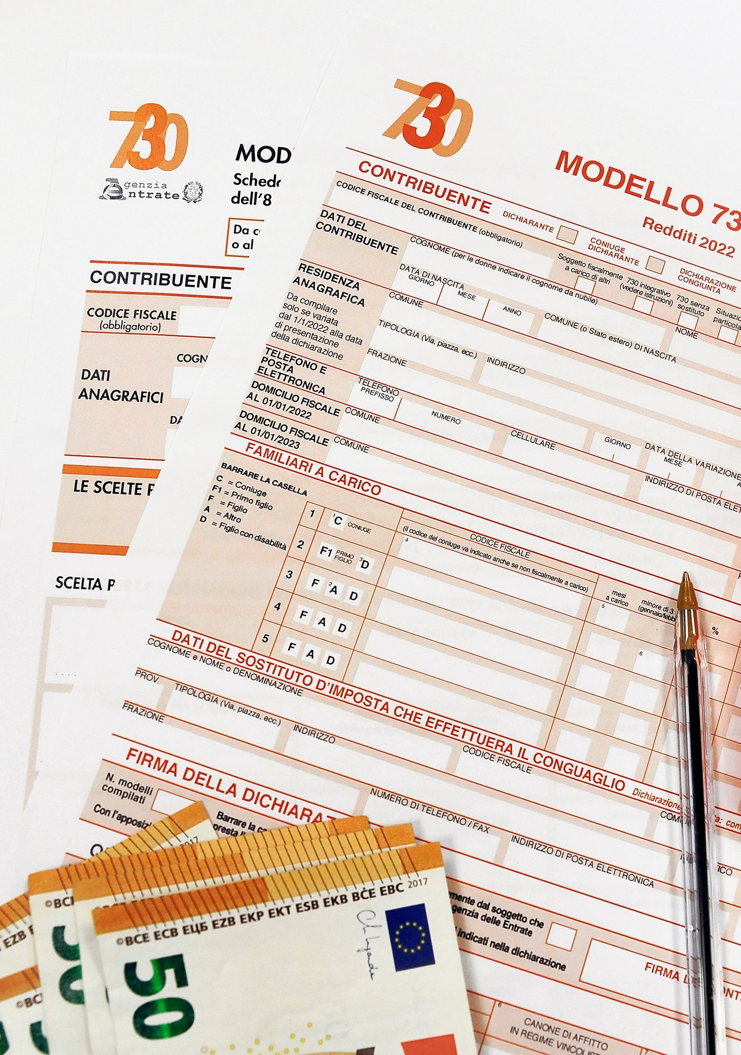 Moduli fiscali italiani, banconote e penna su una superficie bianca.