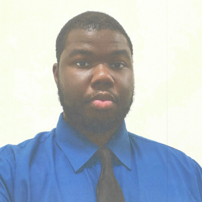 A man with a beard is wearing a blue shirt and tie