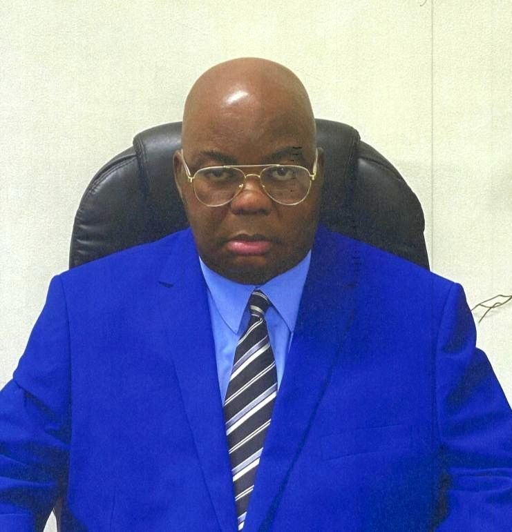 A man in a blue suit and tie is sitting in a chair