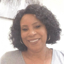 A woman with curly hair and hoop earrings is smiling for the camera.
