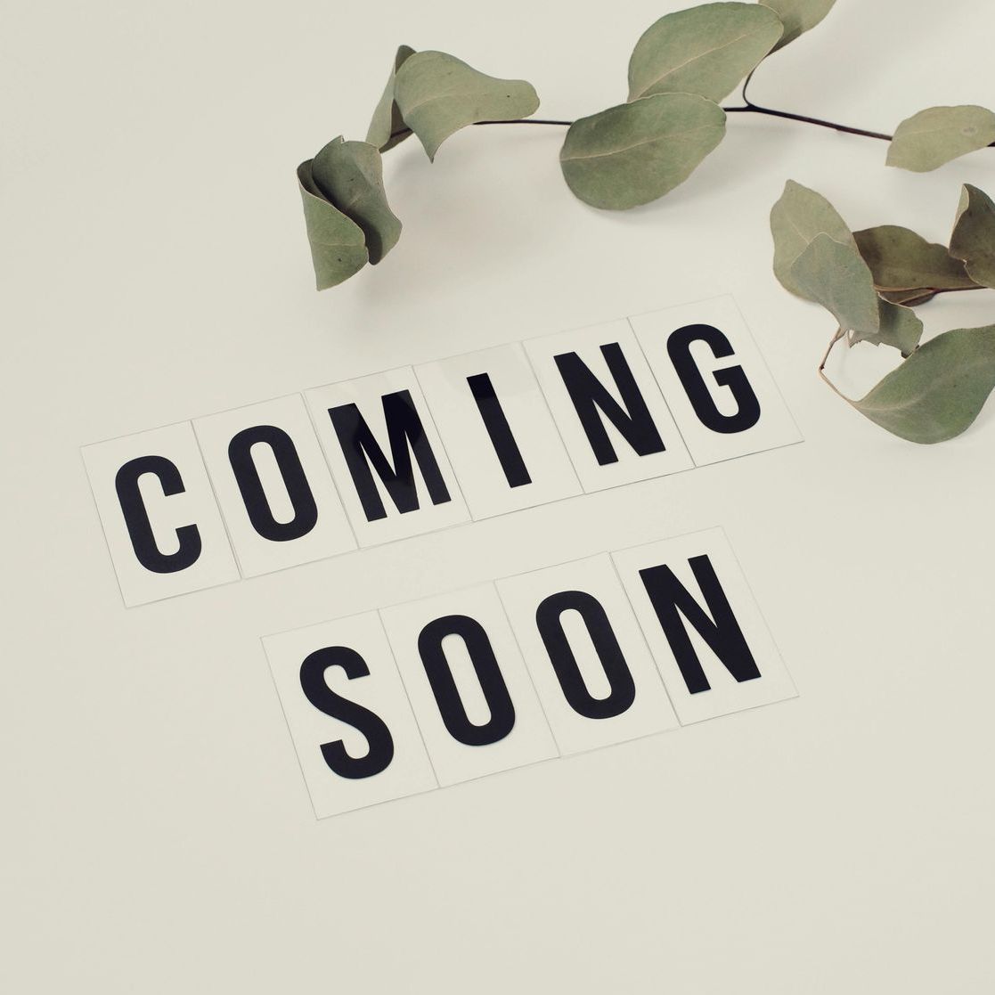 A sign that says coming soon next to some leaves