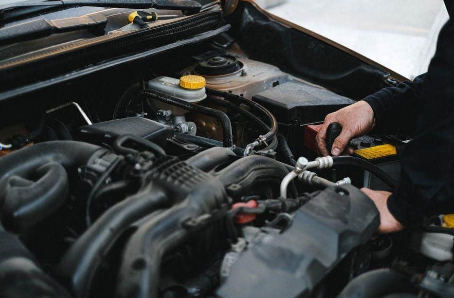 Person working on a car engine under the hood