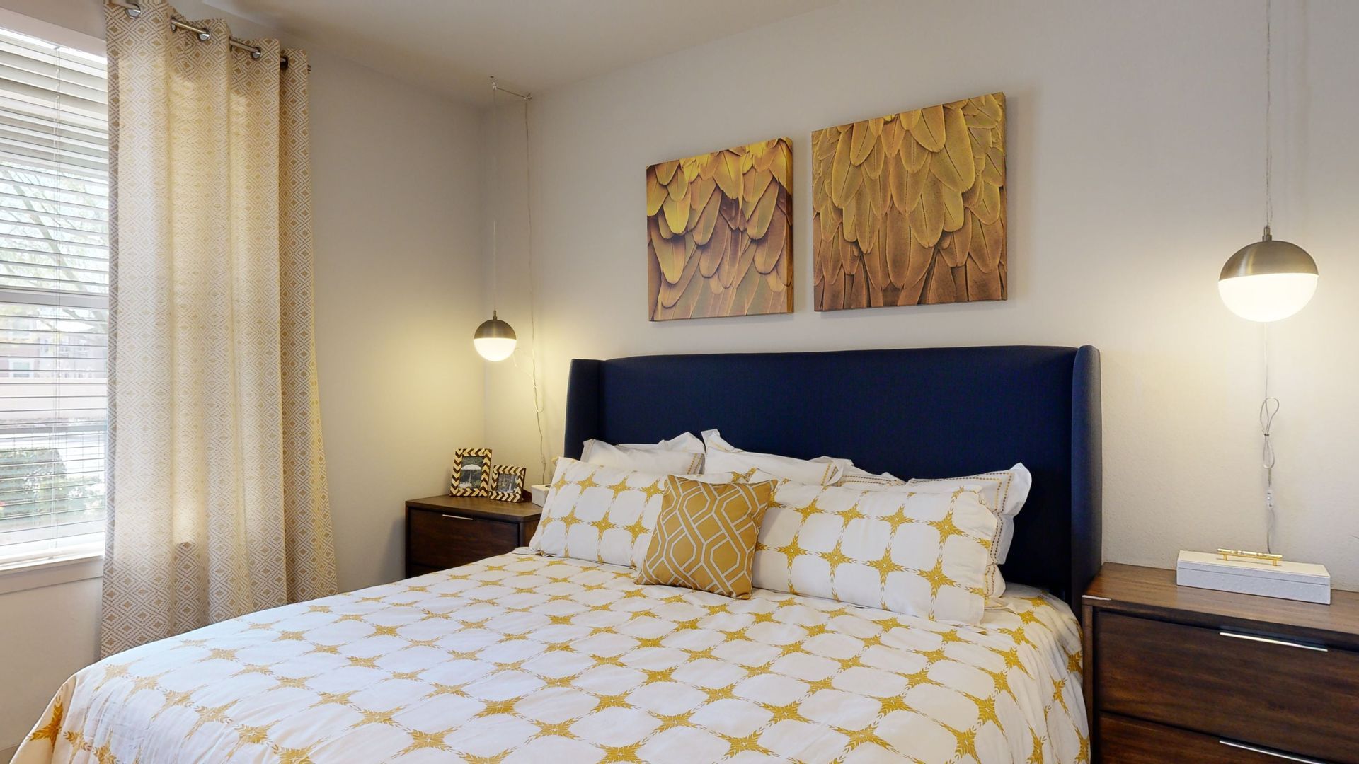 A bedroom with a bed , nightstand , and two paintings on the wall.