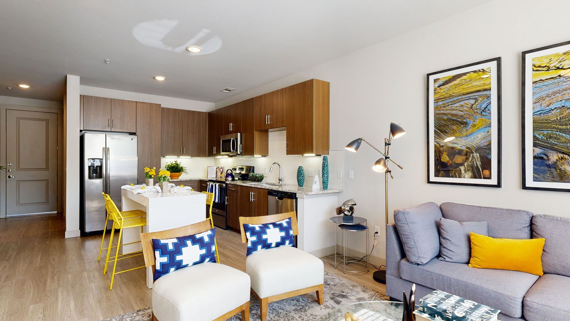 A living room with a couch , chairs , and a kitchen.