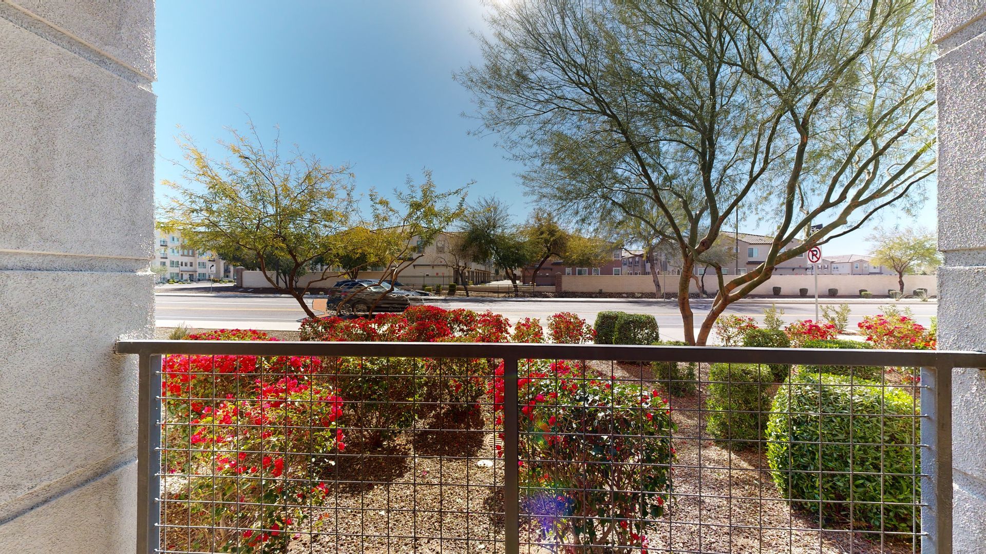 A balcony overlooking a garden with trees and bushes.