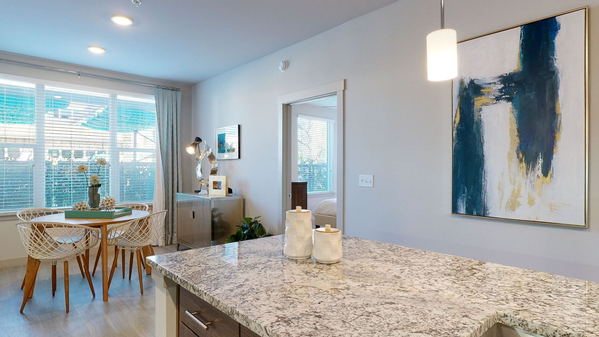 A kitchen with a granite counter top and a painting on the wall.
