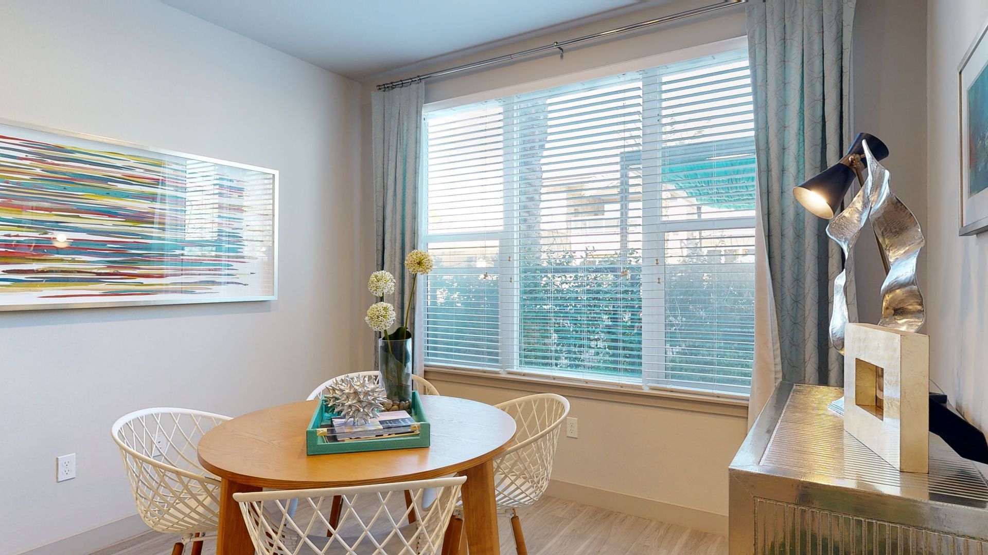 A dining room with a table and chairs and a large window.