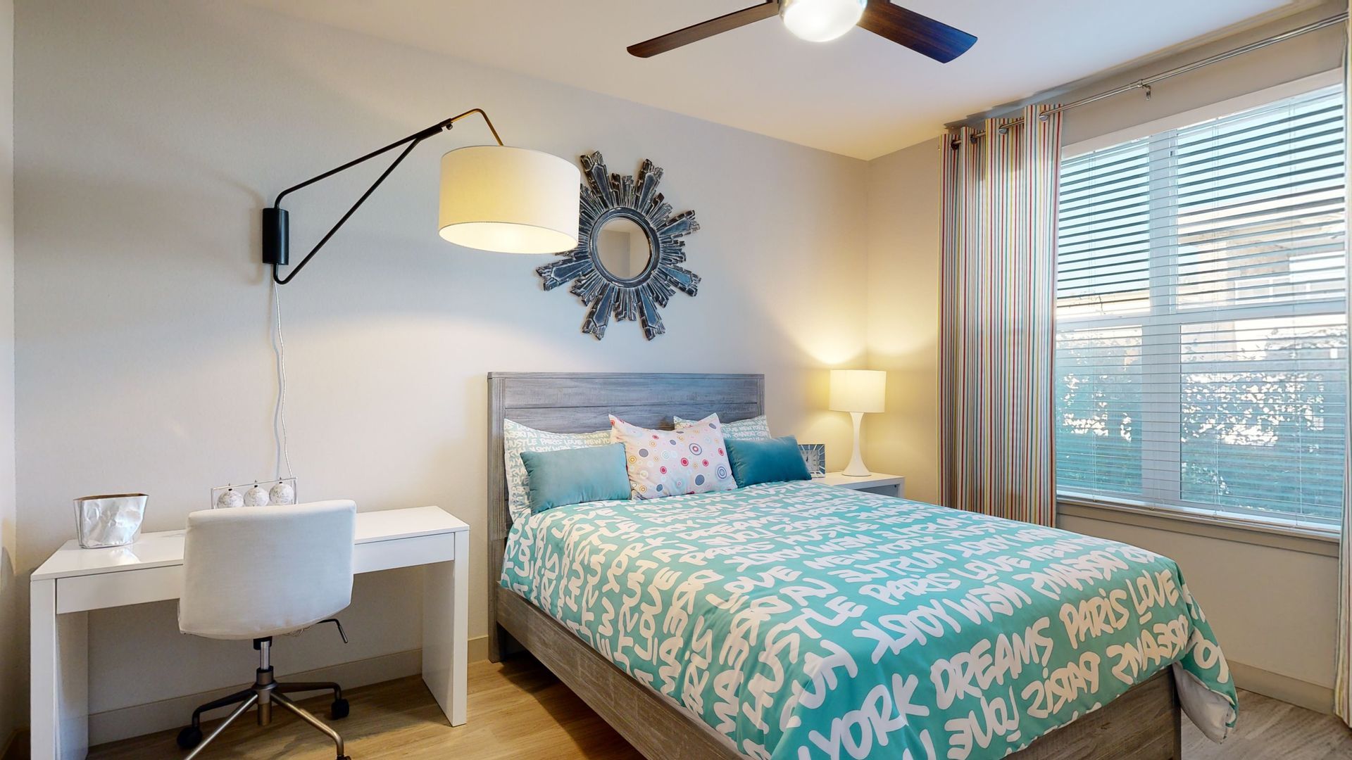A bedroom with a bed , desk , chair and ceiling fan.