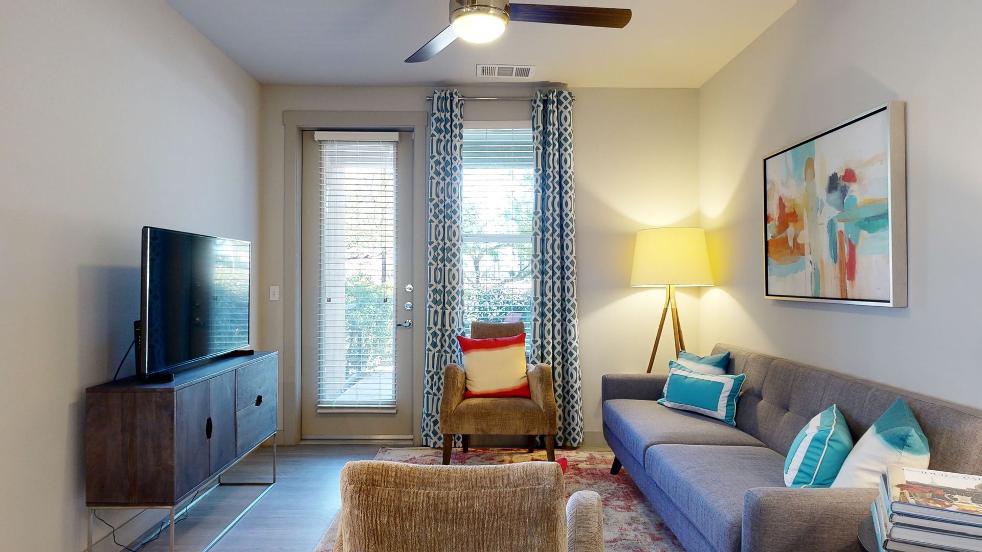 A living room with a couch , chair , television and ceiling fan.