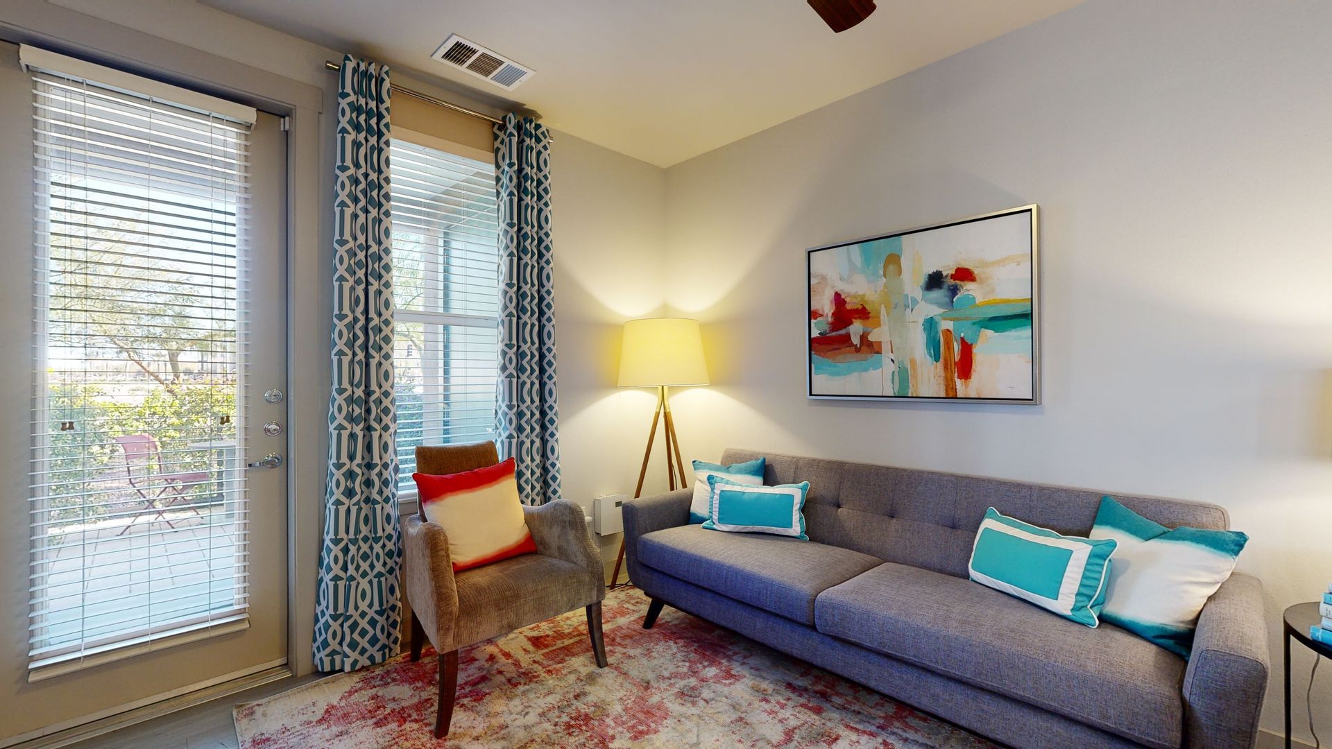 A living room with a couch , chair , lamp and window.