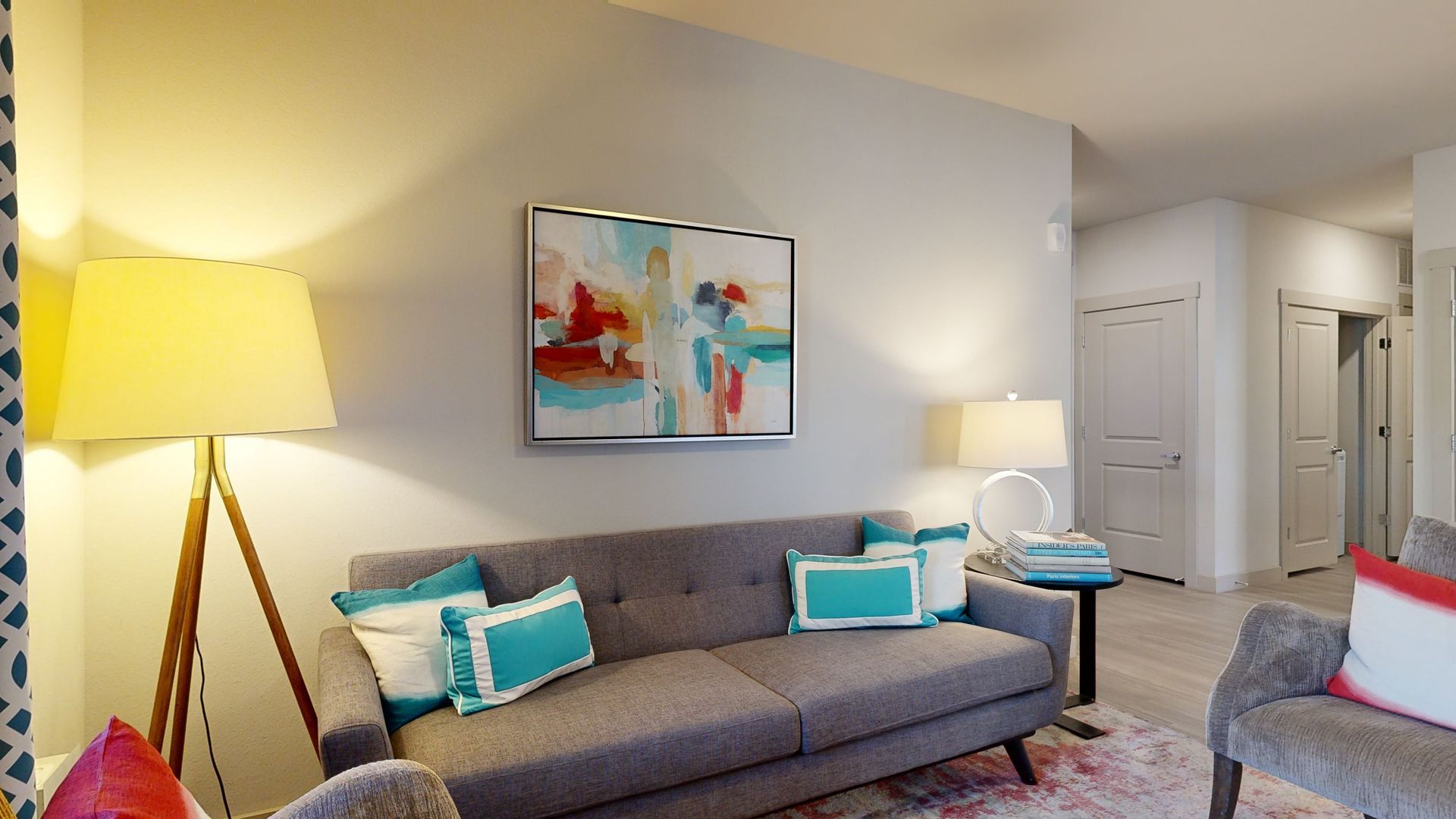 A living room with a couch , chair , lamp and painting on the wall.