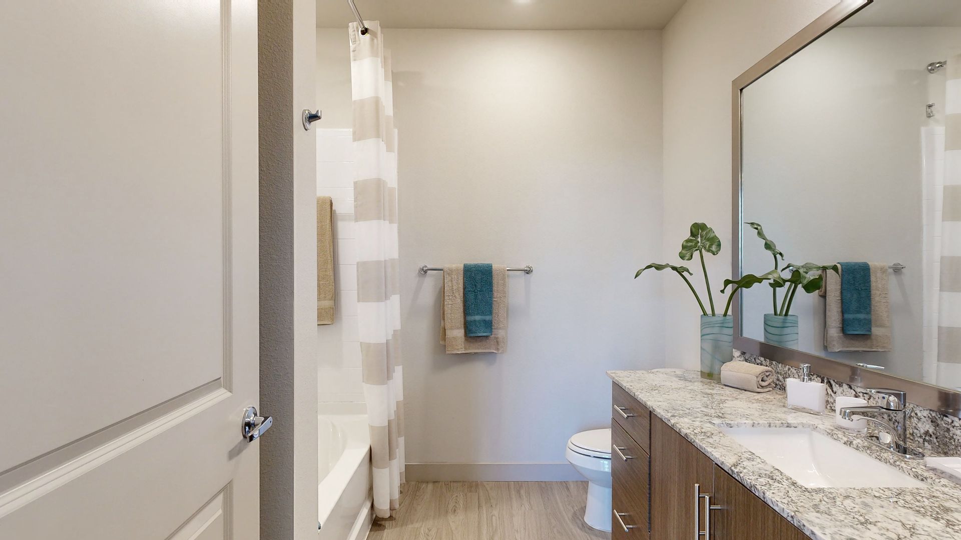 A bathroom with a sink , toilet , shower and mirror.
