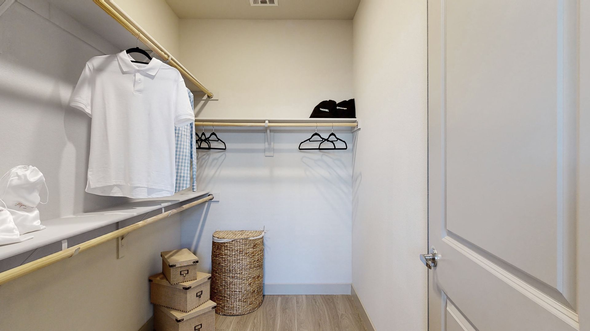 A walk in closet with a lot of shelves and clothes hanging on them.