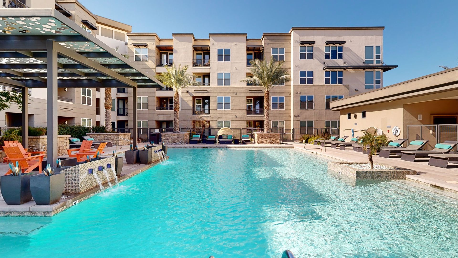 A large swimming pool in front of a large apartment building.