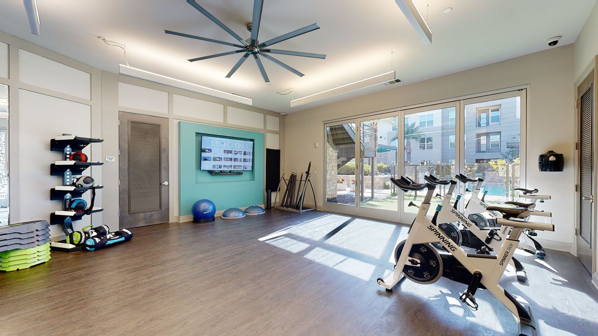 A large room with a lot of windows and a ceiling fan.