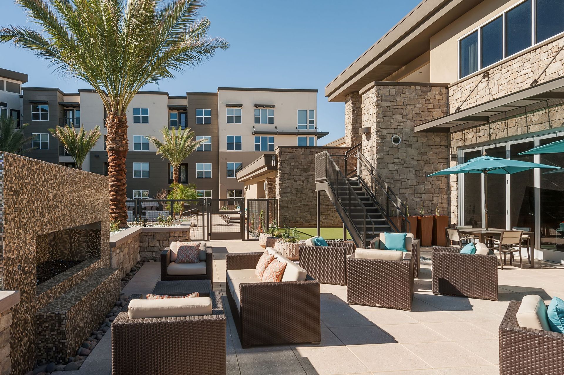 A patio with wicker furniture and umbrellas in front of a building