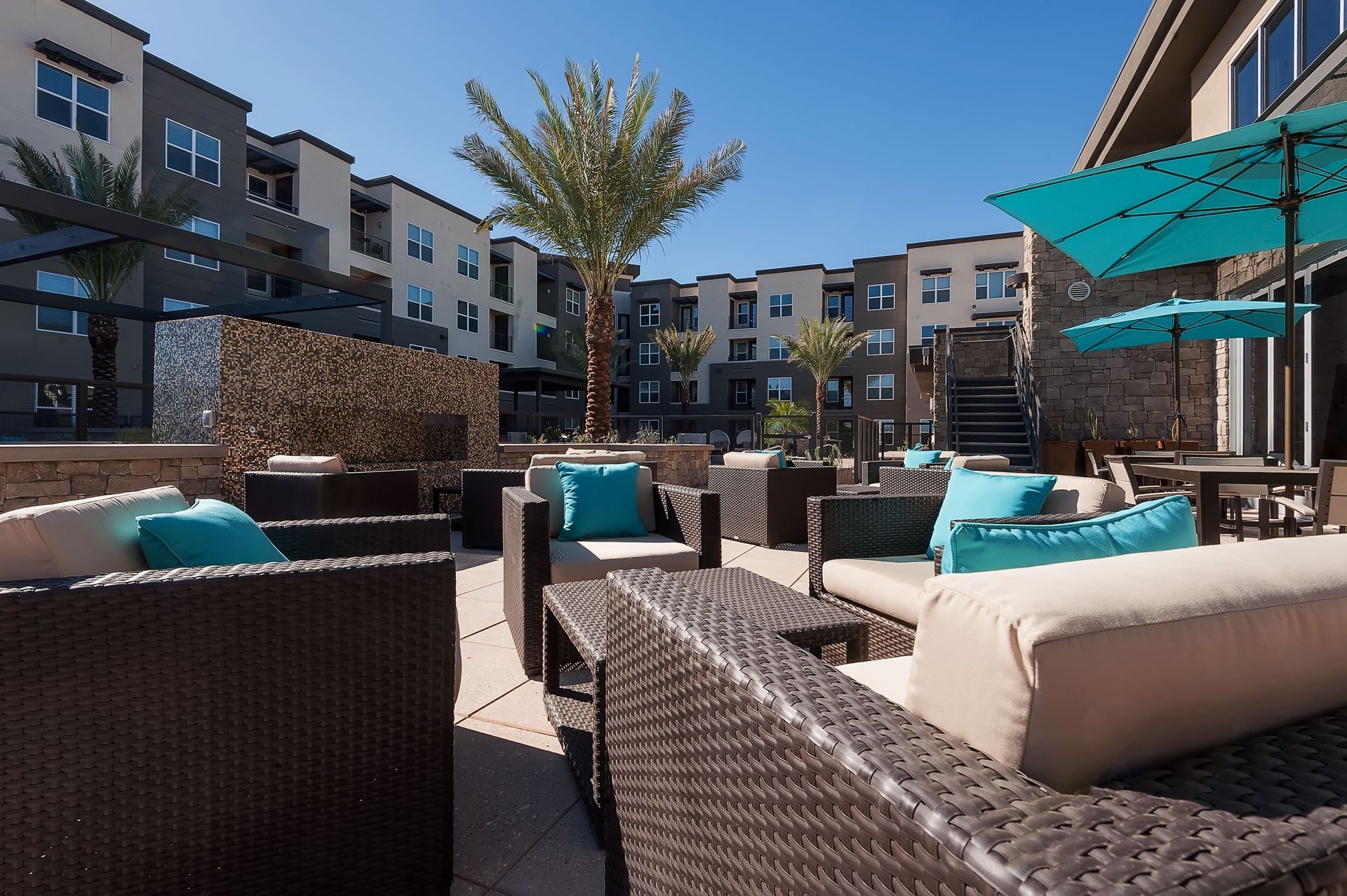 A patio with wicker furniture and umbrellas in front of a building