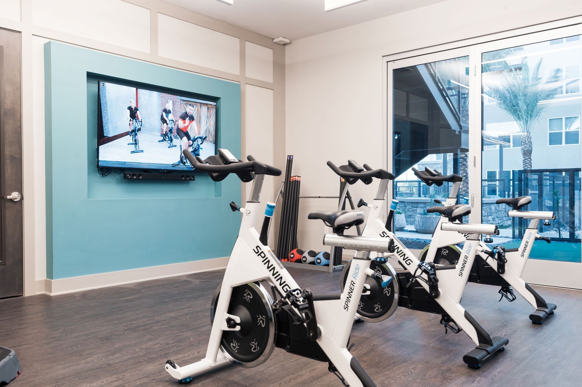A row of exercise bikes in a gym with a television on the wall.