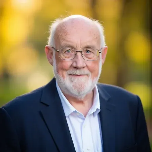A man with glasses is holding a glass of liquid in his hand