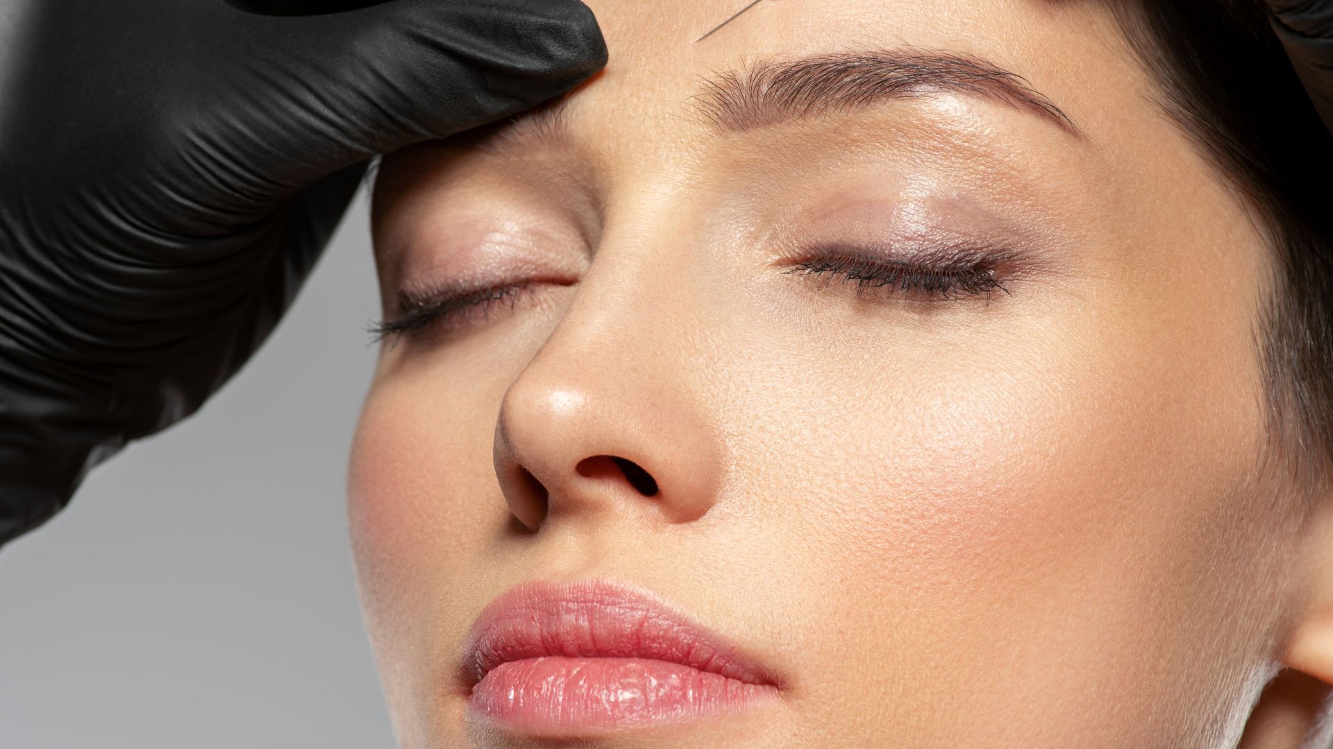 A woman is getting a botox injection in her forehead.