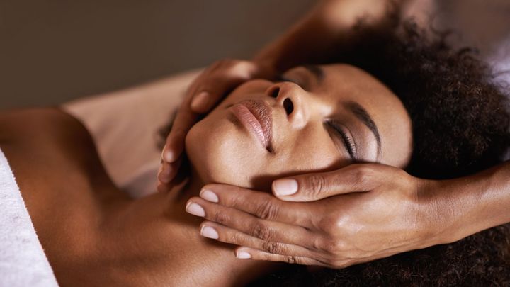 A woman is getting a facial massage at a spa.