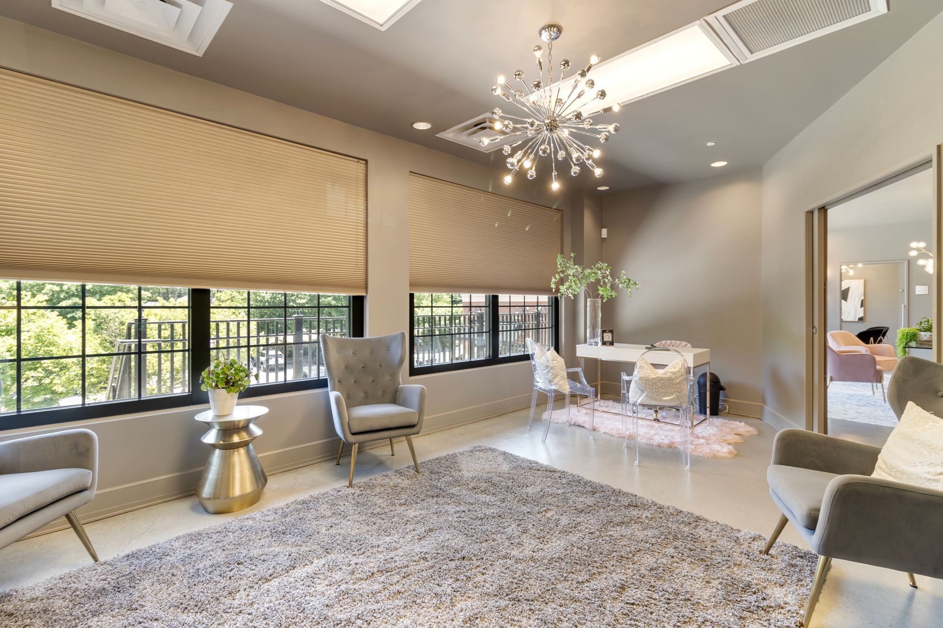 A living room with a rug , chairs , a table and a chandelier. Office Tour