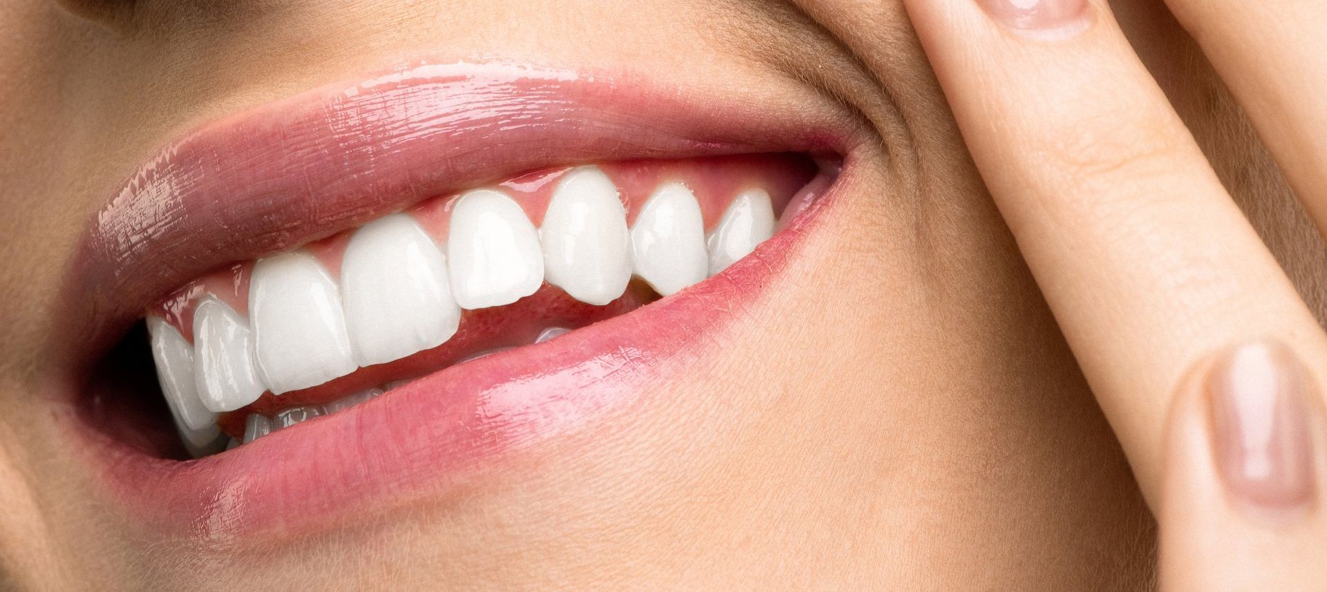 A close up of a woman 's mouth with white teeth and pink lips.