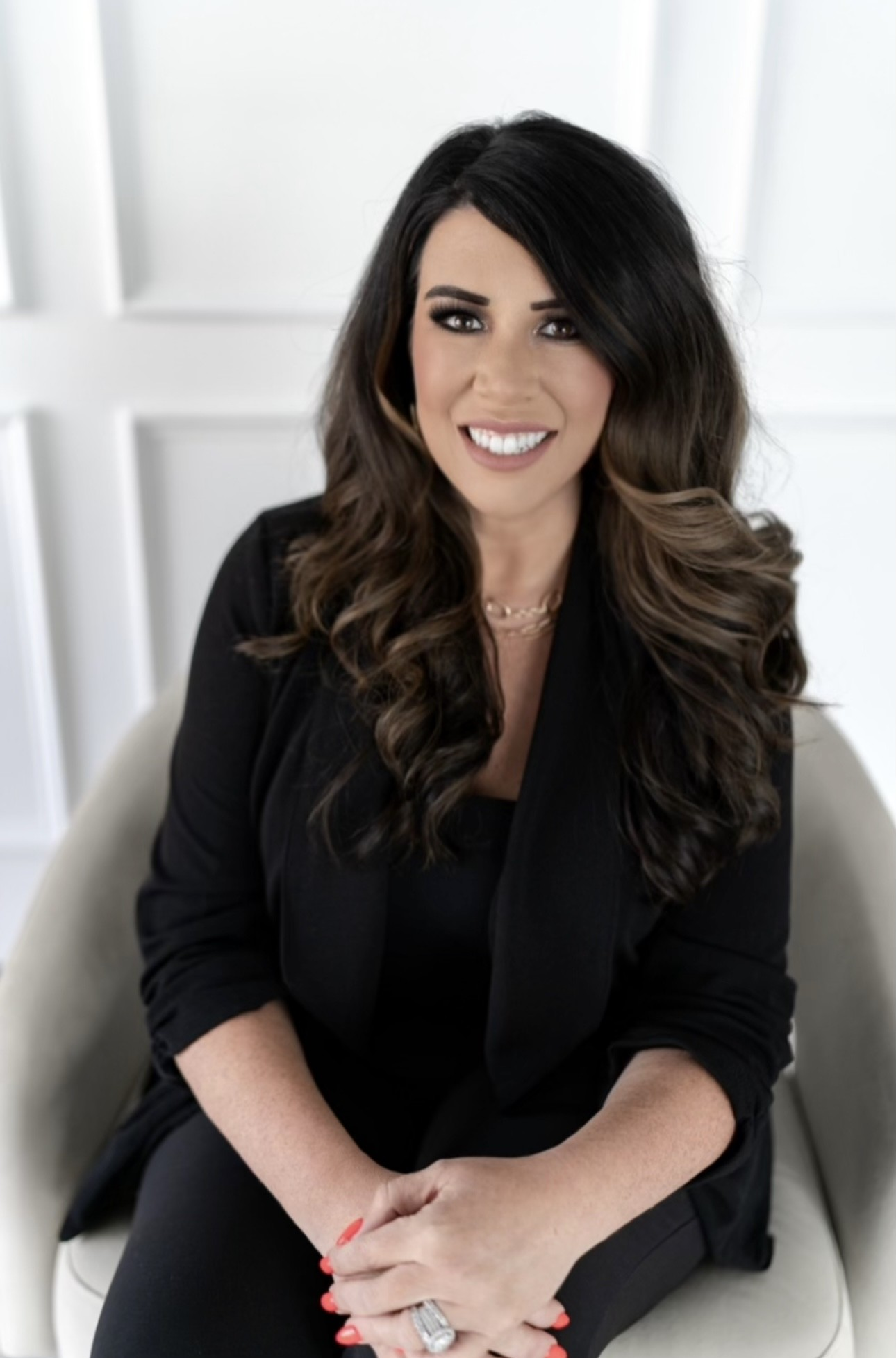 A woman in a black and white jacket is standing with her arms crossed and smiling.