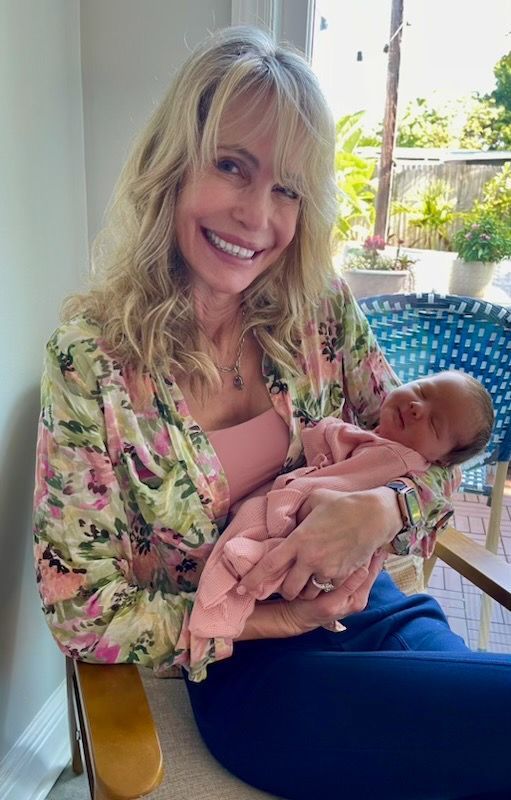 A woman is holding a baby in her arms while sitting in a chair.