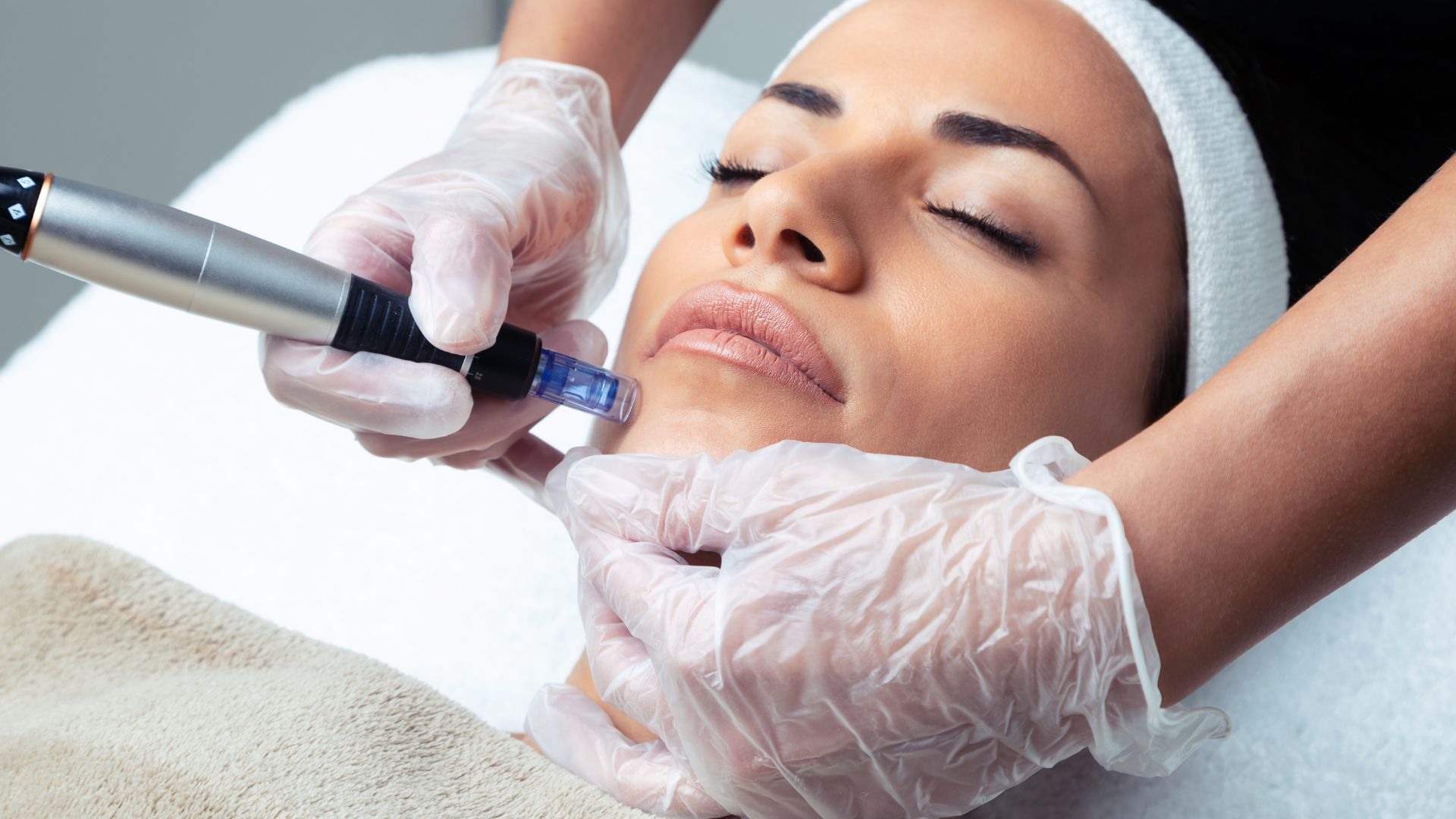 A woman in a green dress is giving a woman a facial treatment.