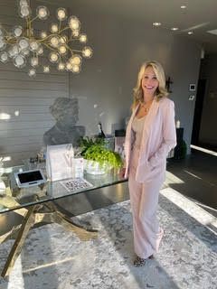 A woman in a pink suit is standing in front of a glass desk.