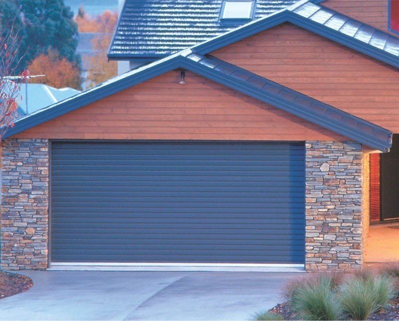 A house with a blue garage door and a stone wall