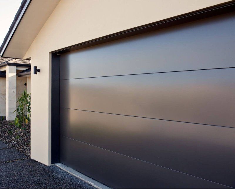 A black garage door is on the side of a house